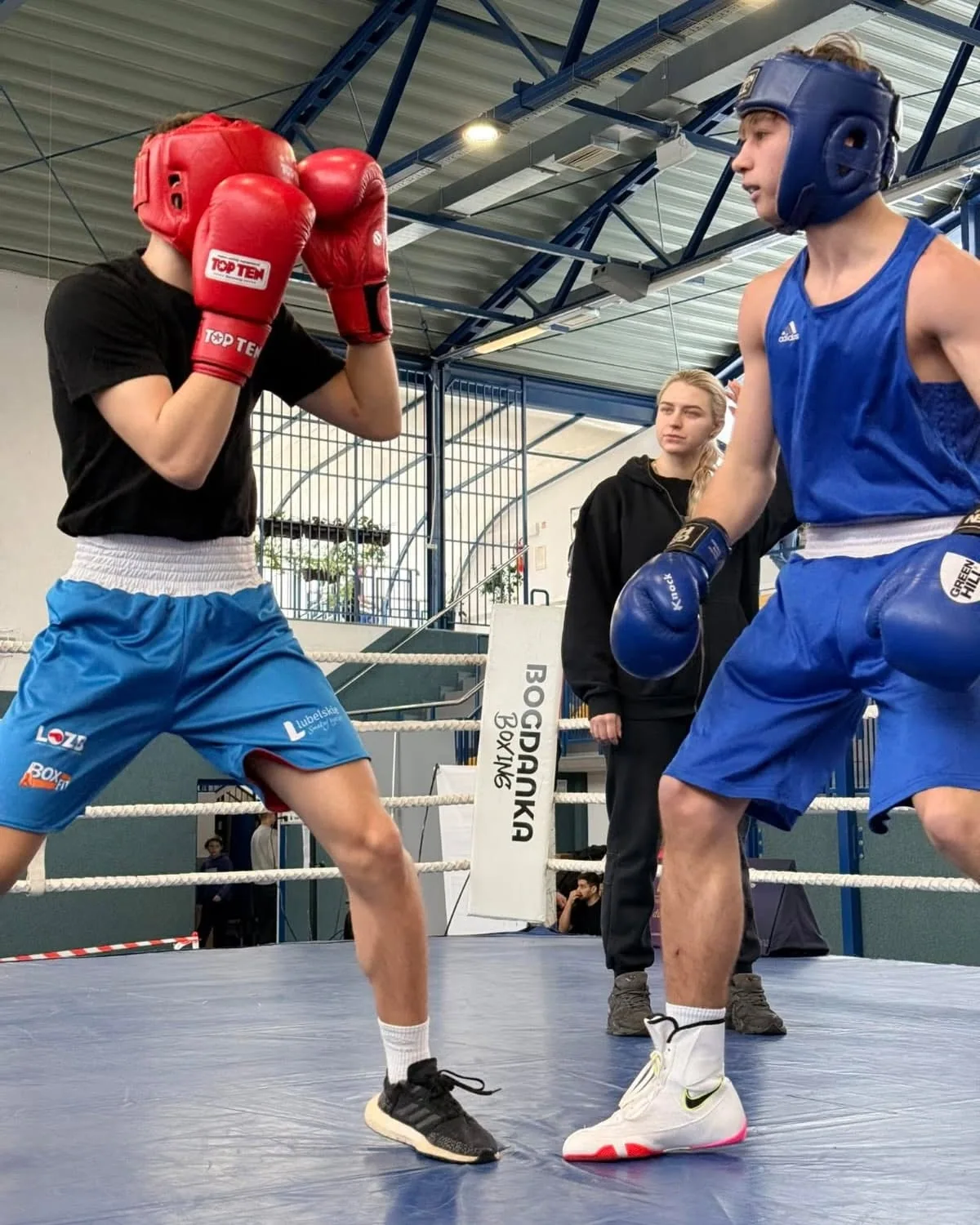 Sparing młodzieży na ringu treningowym — zawodnik w czerwonych rękawicach w gardii naprzeciw rywala